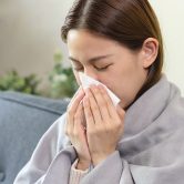 Image of a woman experiencing a cold wrapped in a blanket